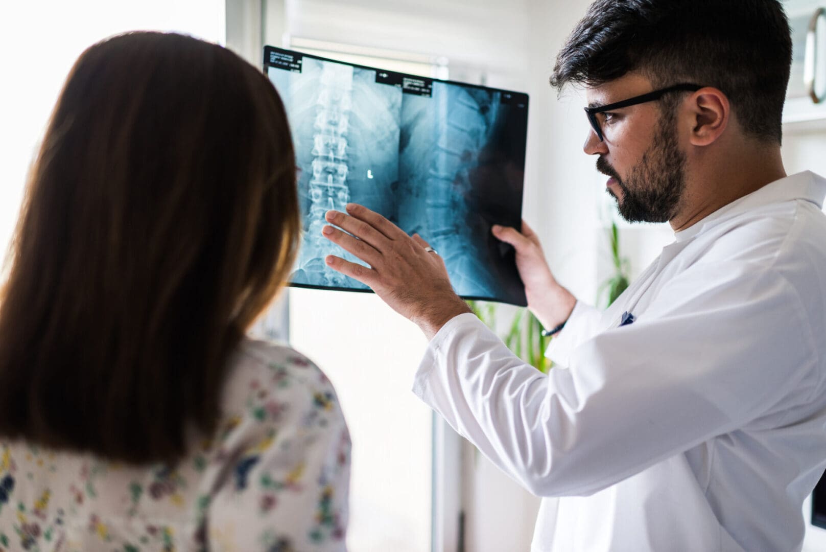 Doctor explaining spine X-ray to patient.